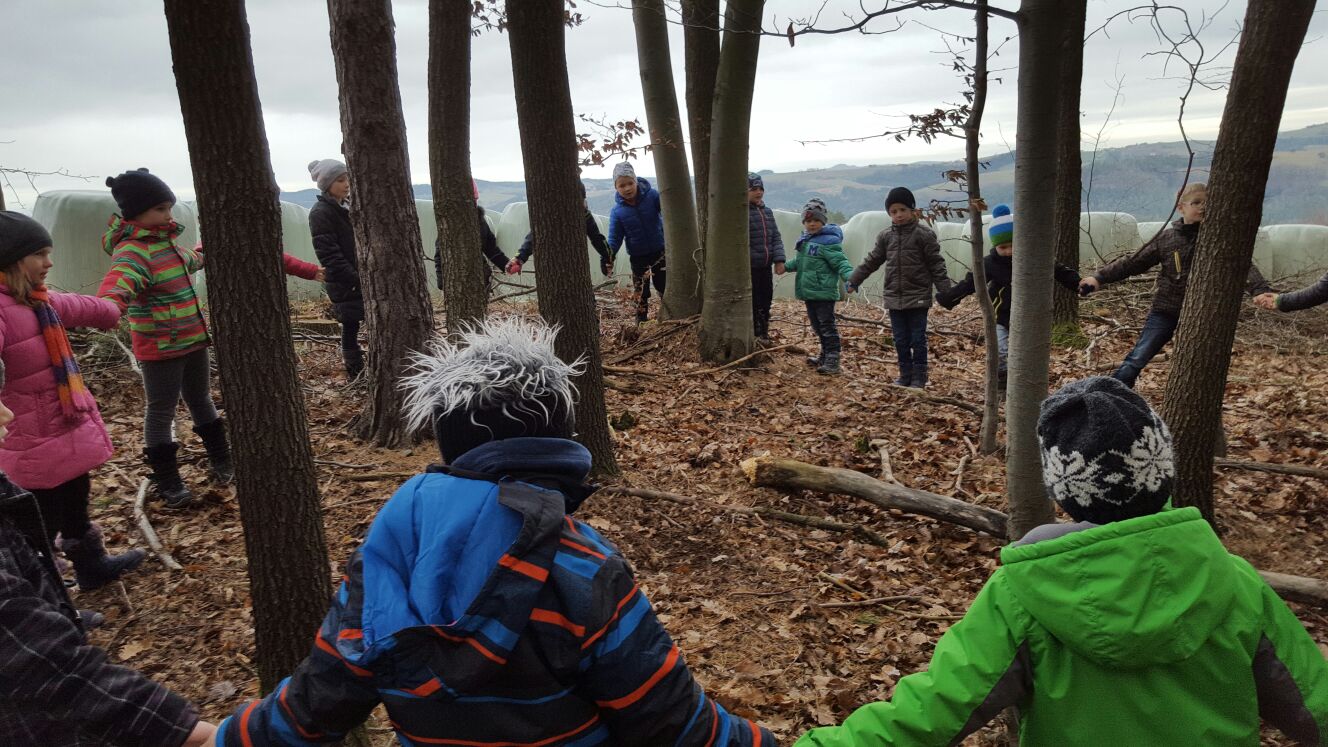 Kinder stehen im Kreis um Bäme